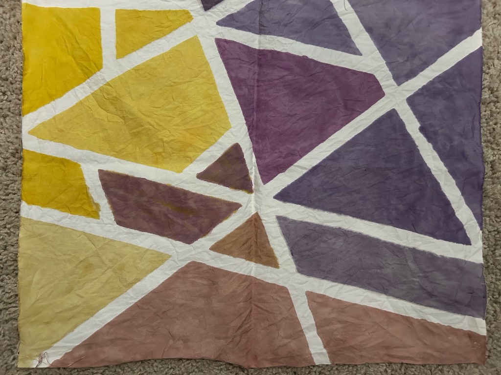 Geometric design with shapes of purple and blue and yellow hues with intersecting white lines throughout. 
