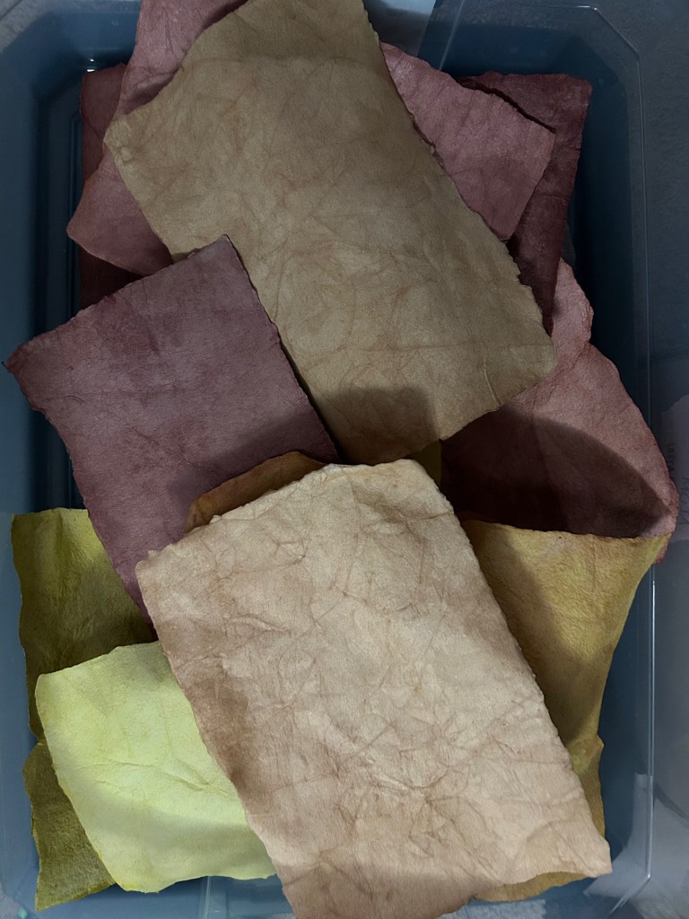 A haphazard stack of various colors of handmade paper that haven't been pressed flat.