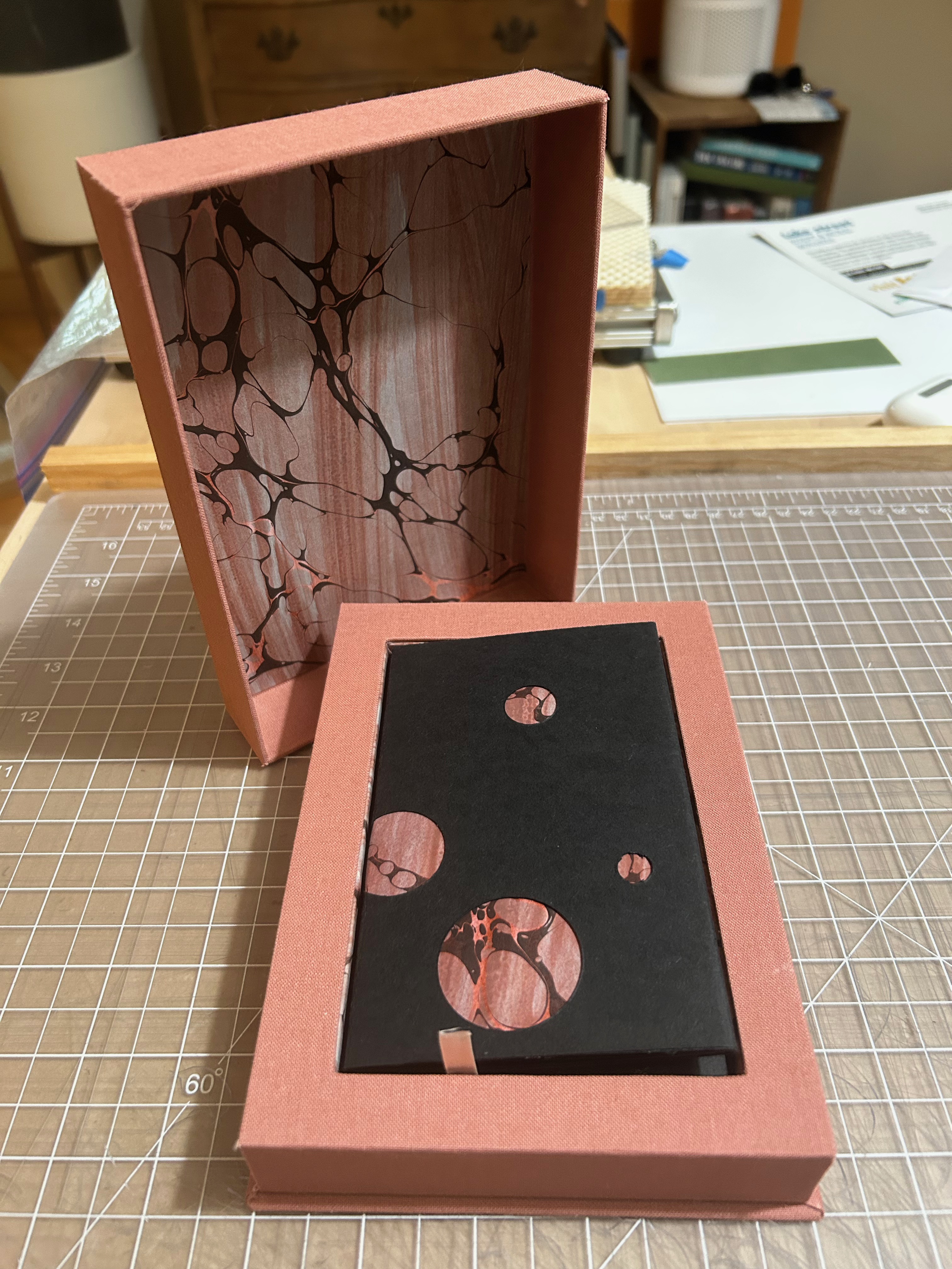 Mauve telescoping box enclosure with black book inside.