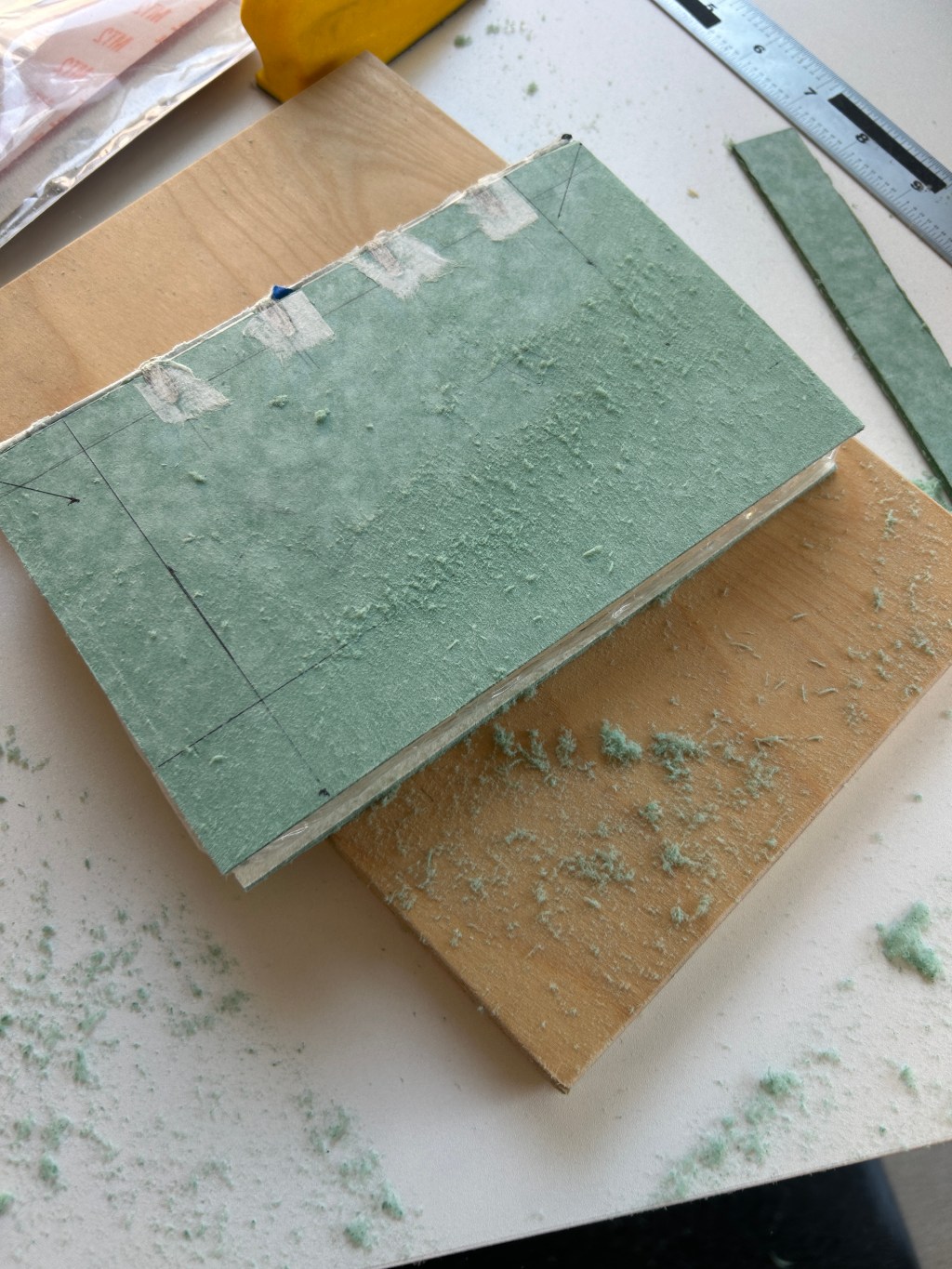 book with green boards is being sanded on a workbench